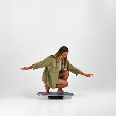 Woman on the Indo balance board featuring the original model and flow cushion. Bamboo Beach design by Drew Brophy.