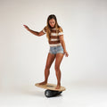 Woman on the Indo balance board featuring the original model and performance roller. Natural stain graphic. 