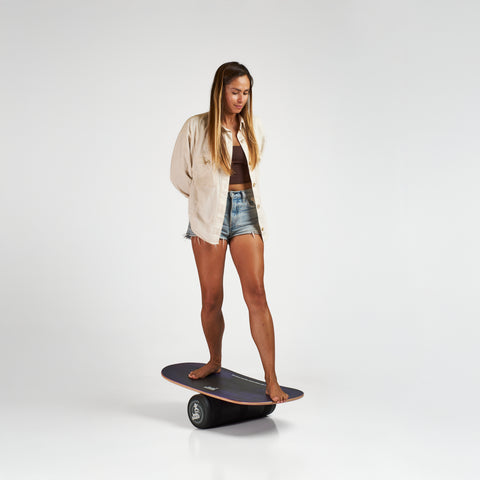 Woman on the Indo balance board featuring the Rocker model and performance roller. Purple Rain design. 